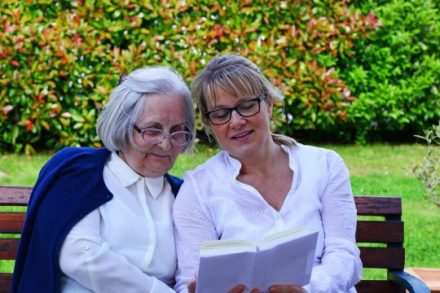 Betreuerin liest Seniorin Buch vor